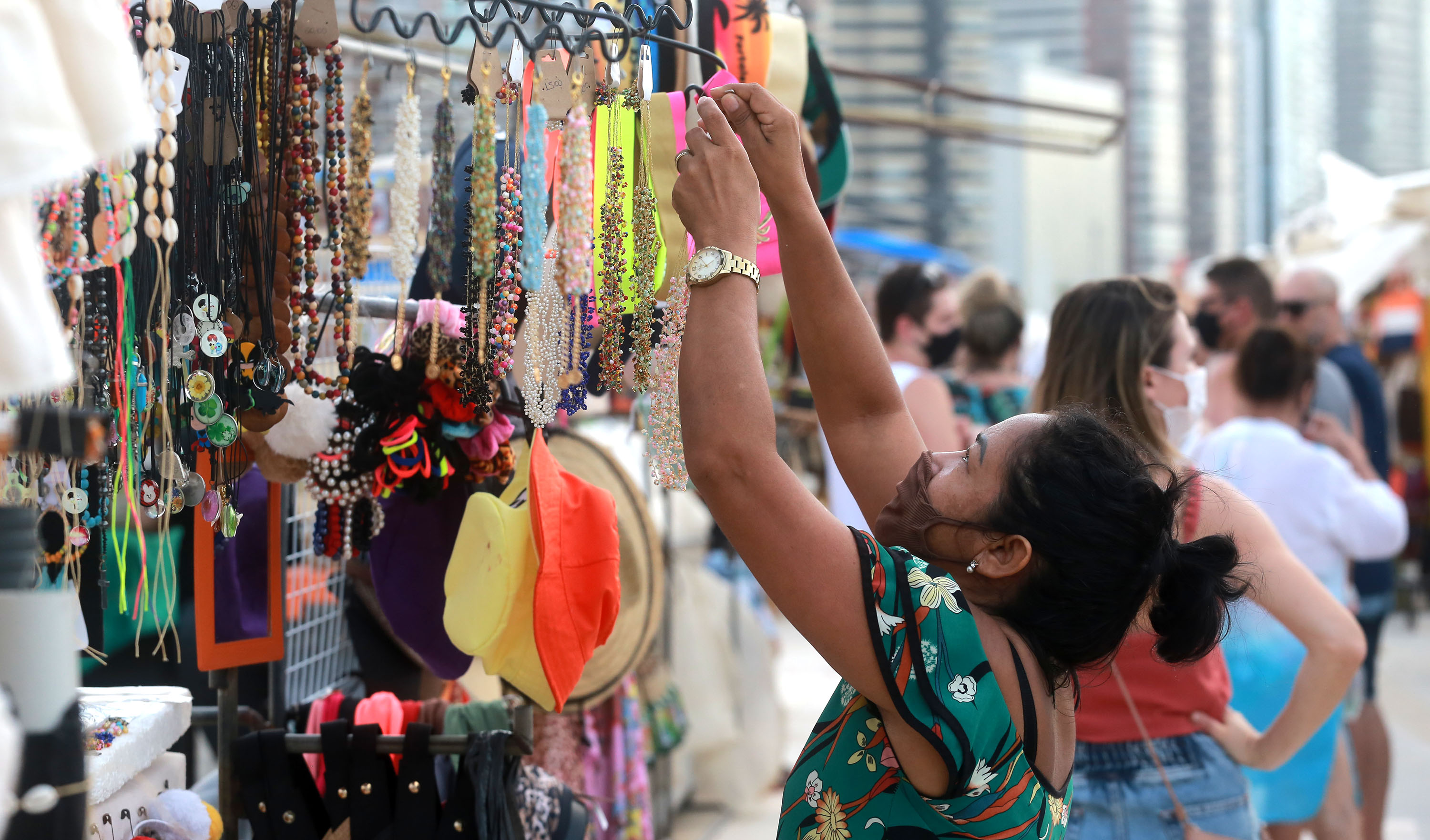 mulher ajeita os produtos em um quiosque de bijoterias